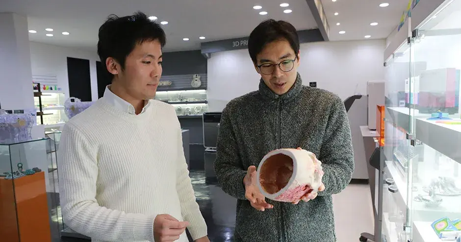 3D プリントを見ている 2 人の同僚