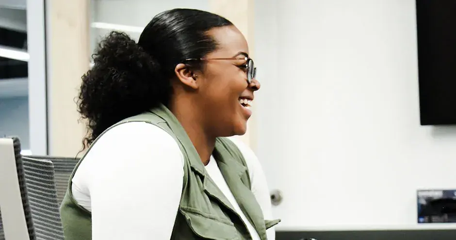 机に向かって座ってほほえむ同僚