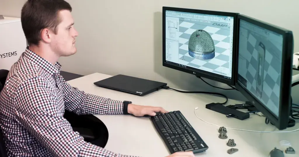 a man sitting at a desk with 3D printed parts